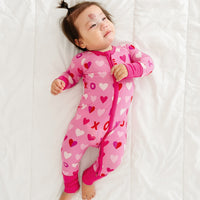 Child laying on a bed wearing a Pink XOXO zippy