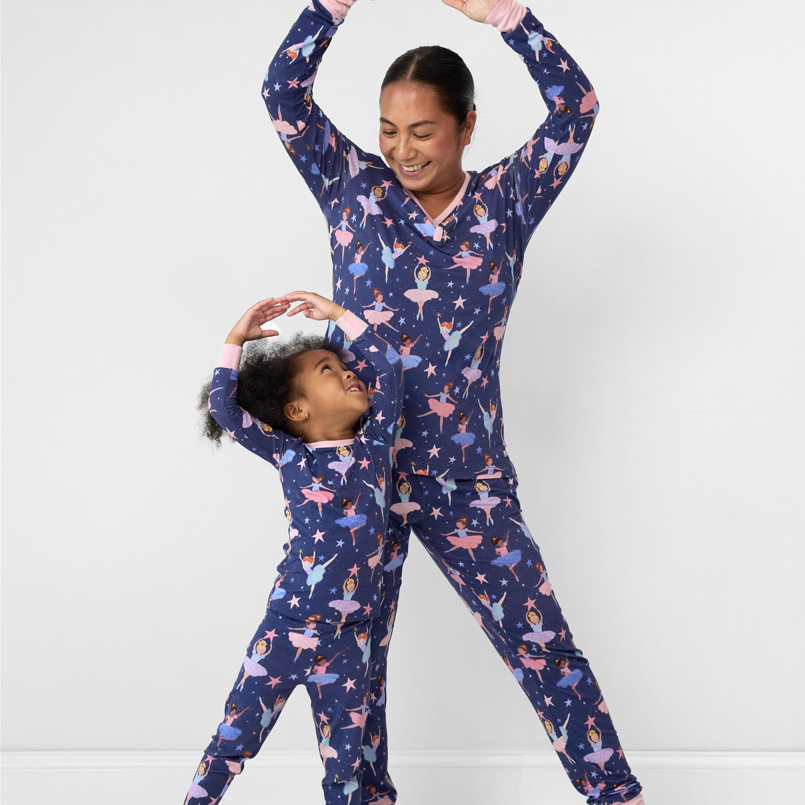 Image of a mother and daughter dancing wearing matching Twilight Ballet pjs in women's top and bottom and children's two piece sets