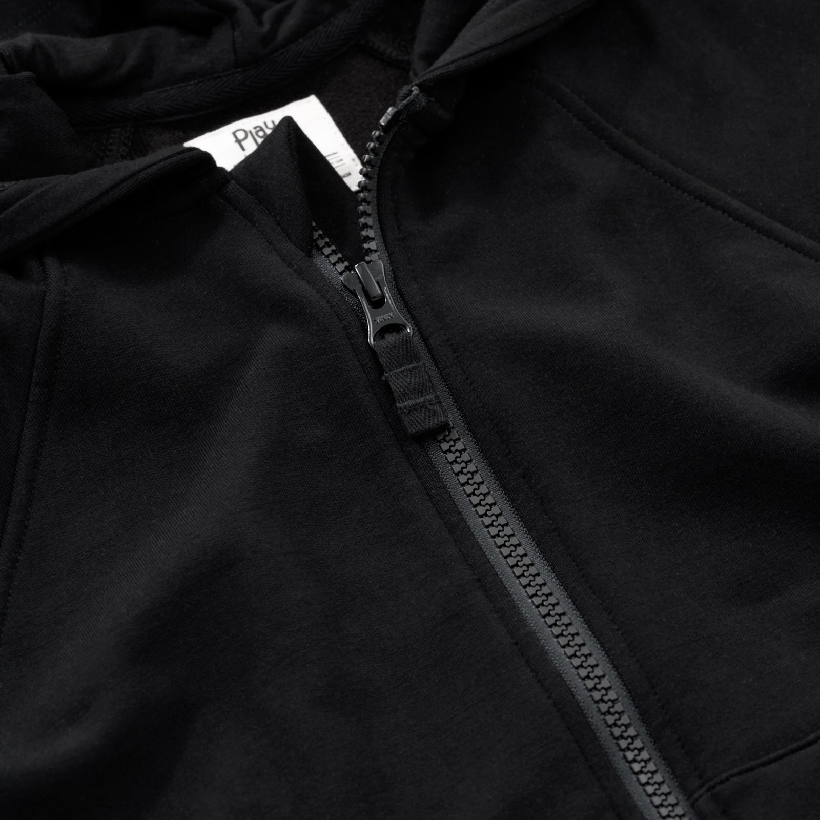 Close up flat lay image of the zipper detail on the Black Zip Hoodie
