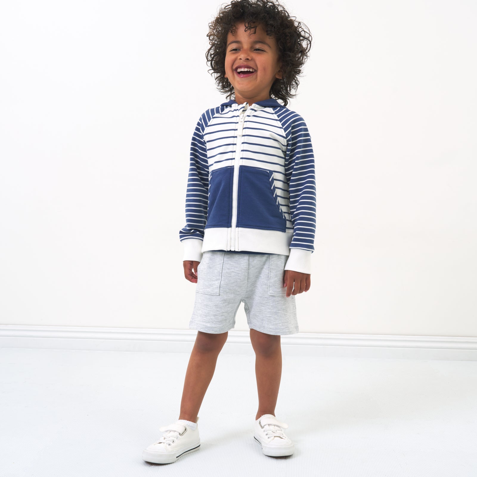 Child posing witChild wearing a Vintage Navy and Ivory Stripes zip hoodie paired with light heather gray shorts