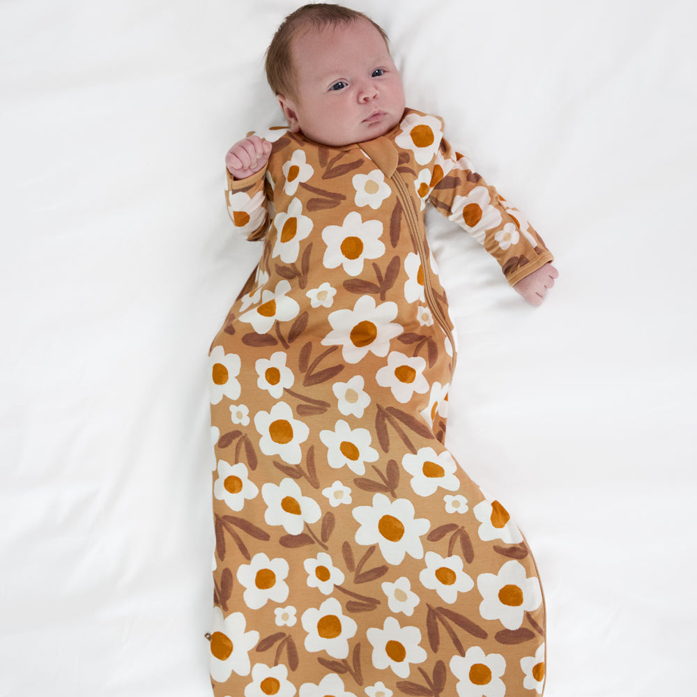 Image of a child laying in bed wearing a Daisy Daydream sleepy bag