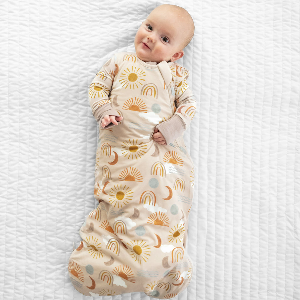 Child laying on a bed in a Desert Sunrise printed sleepy bag