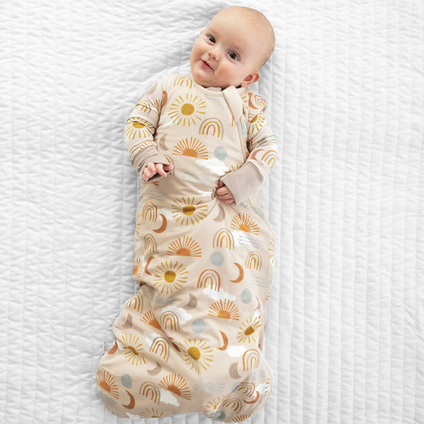 Child laying on a bed in a Desert Sunrise printed sleepy bag