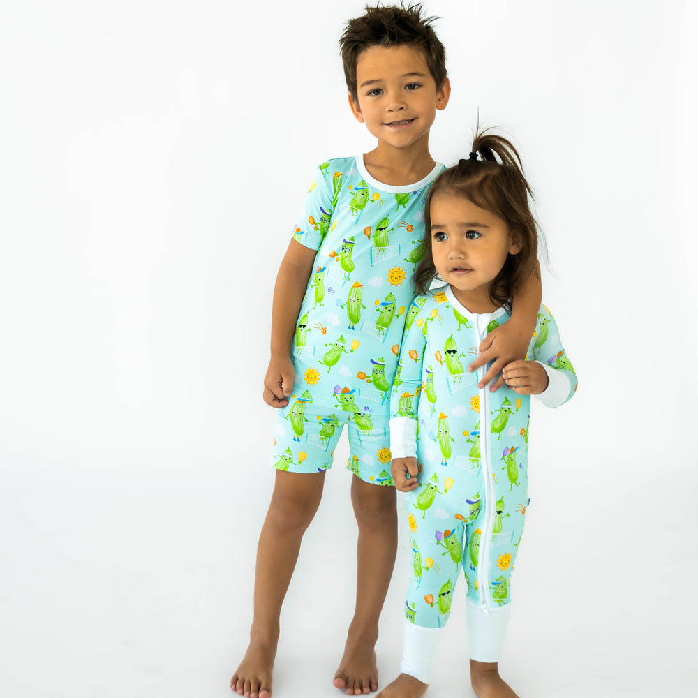 Two children wearing the Pickle Power. Boy on the left is wearing a Pickle Power Two-Piece Short Sleeve & Shorts Pajama Set and child on the left is wearing the Pickle Power Zippy