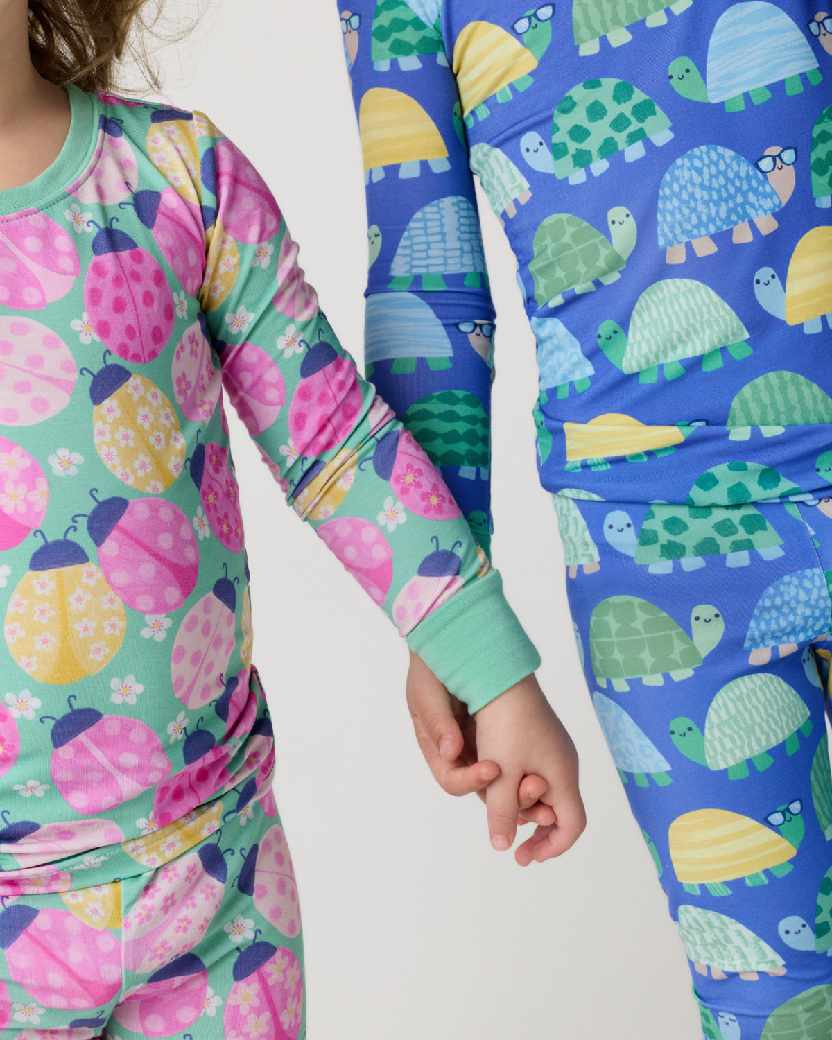 Close up of two children holding hands wearing animal print pajamas
