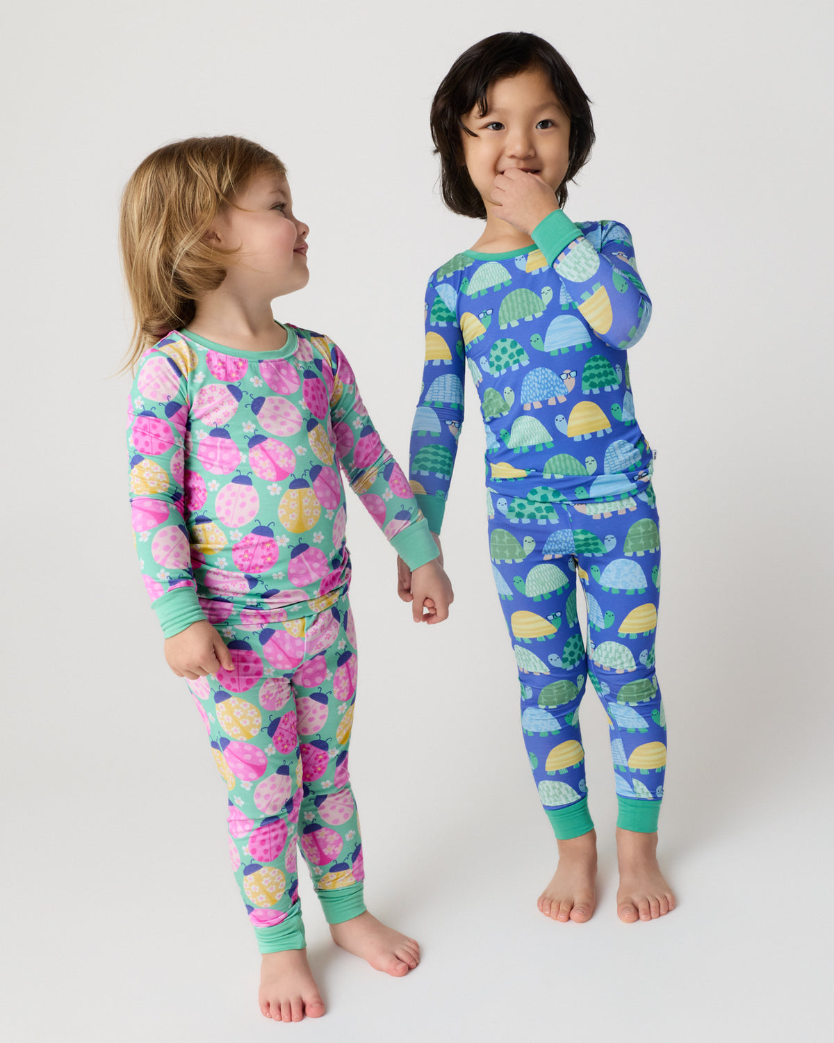 Two children wearing Ladybug Meadow and Shell Parade Two-Piece Pajama Sets