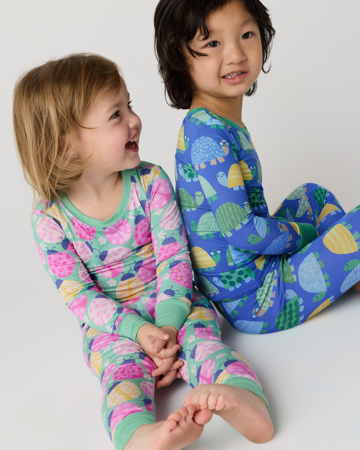 Two sitting children wearing animal print kids pajamas