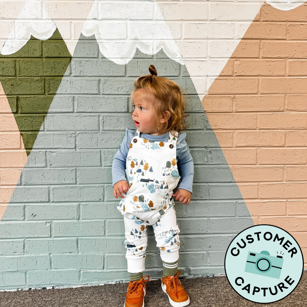 Customer Capture image of a child wearing Lets Explore Overalls paired with a Fog Bodysuit