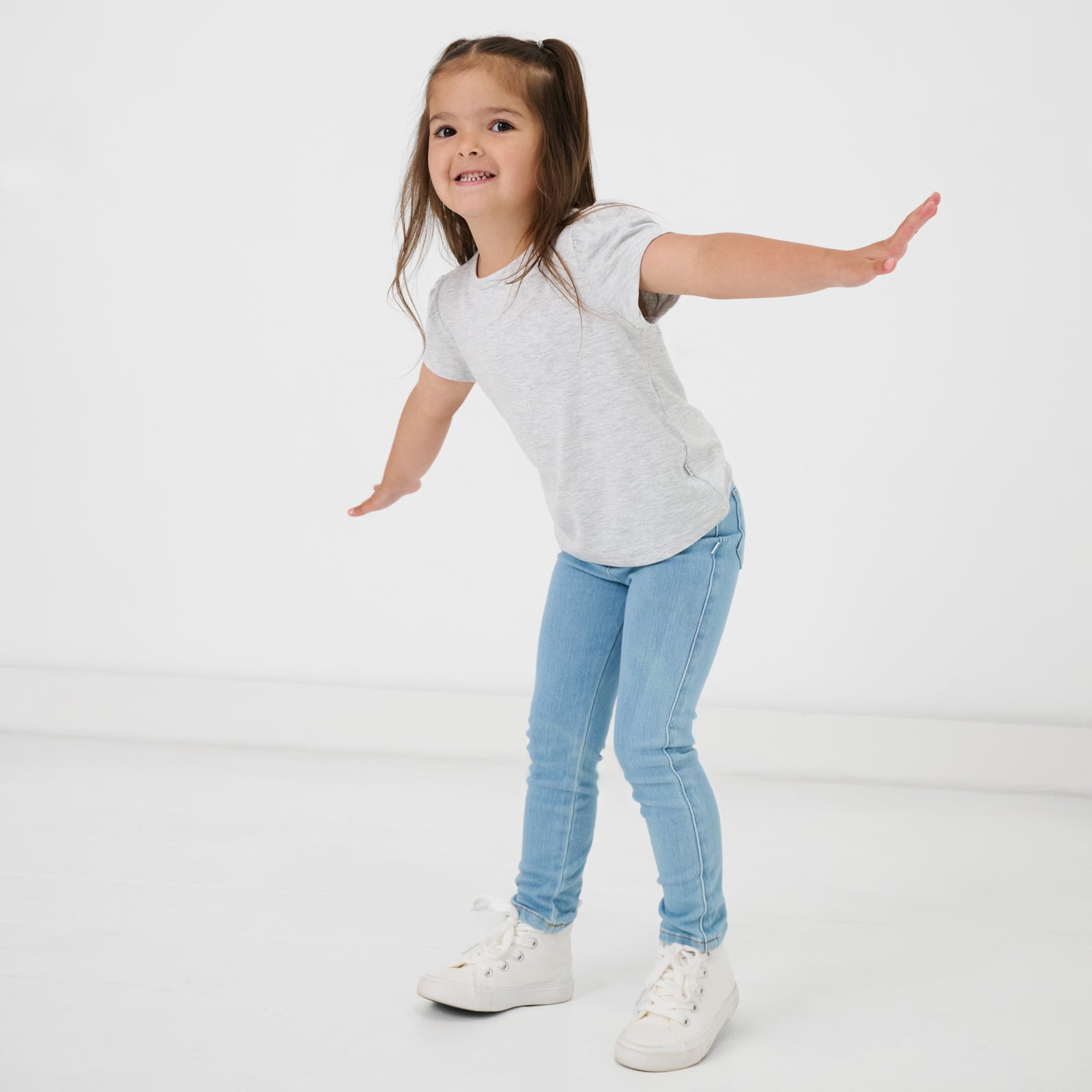 Posing child wearing the Light Blue Denim Jegging with a gray tshirt