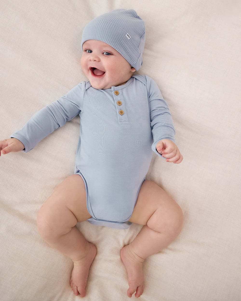 Aerial view of baby wearing the Light Fog Henley Bodysuit