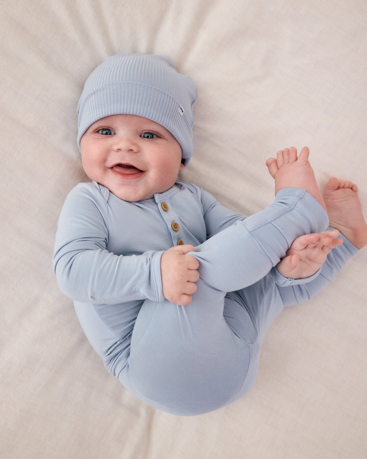 Aerial view of baby on a white blanket wearing the Light Fog Fold-Over Legging