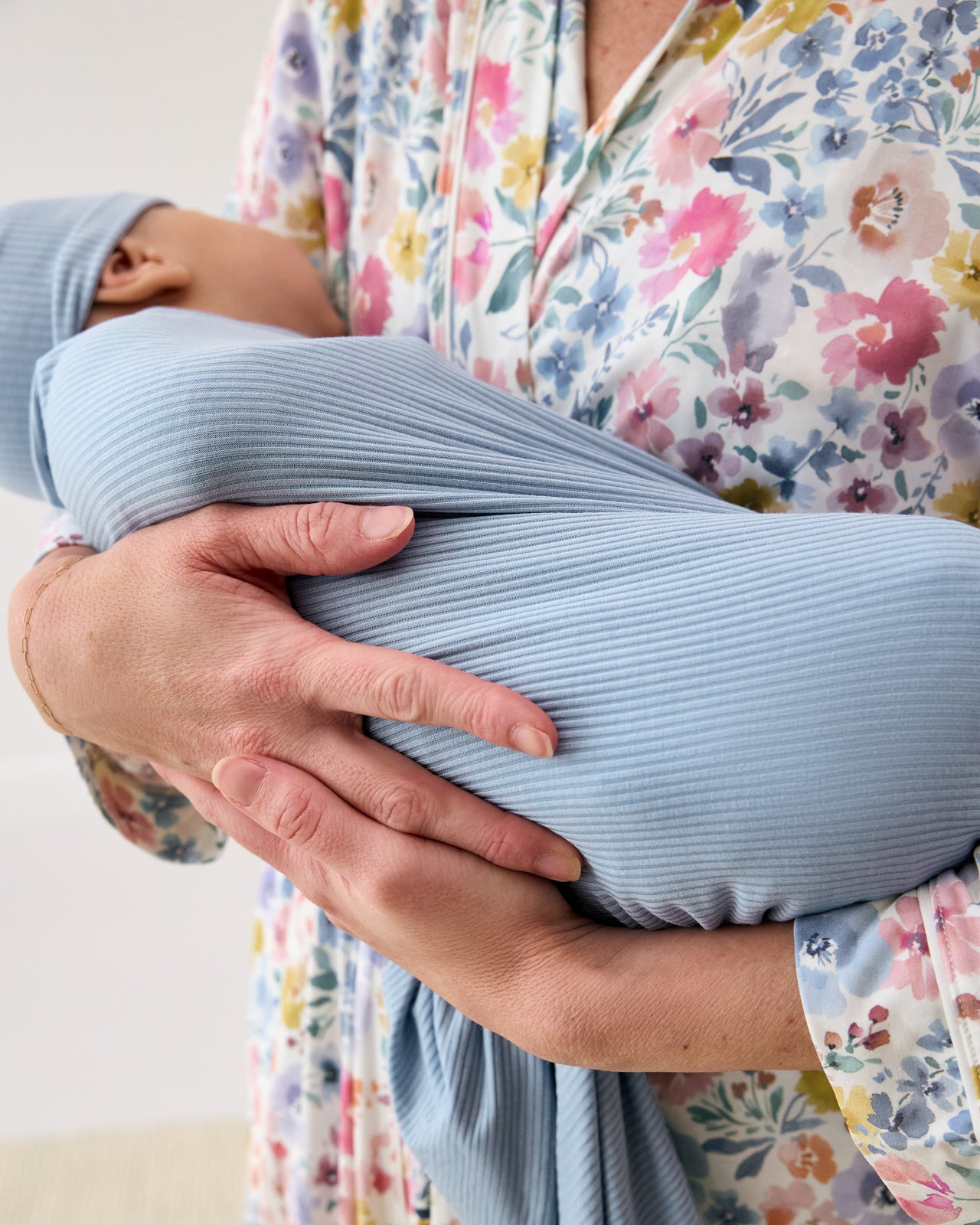 Woman holding newborn wearing the Light Fog Baby Ribbed Swaddle & Infant Beanie Set