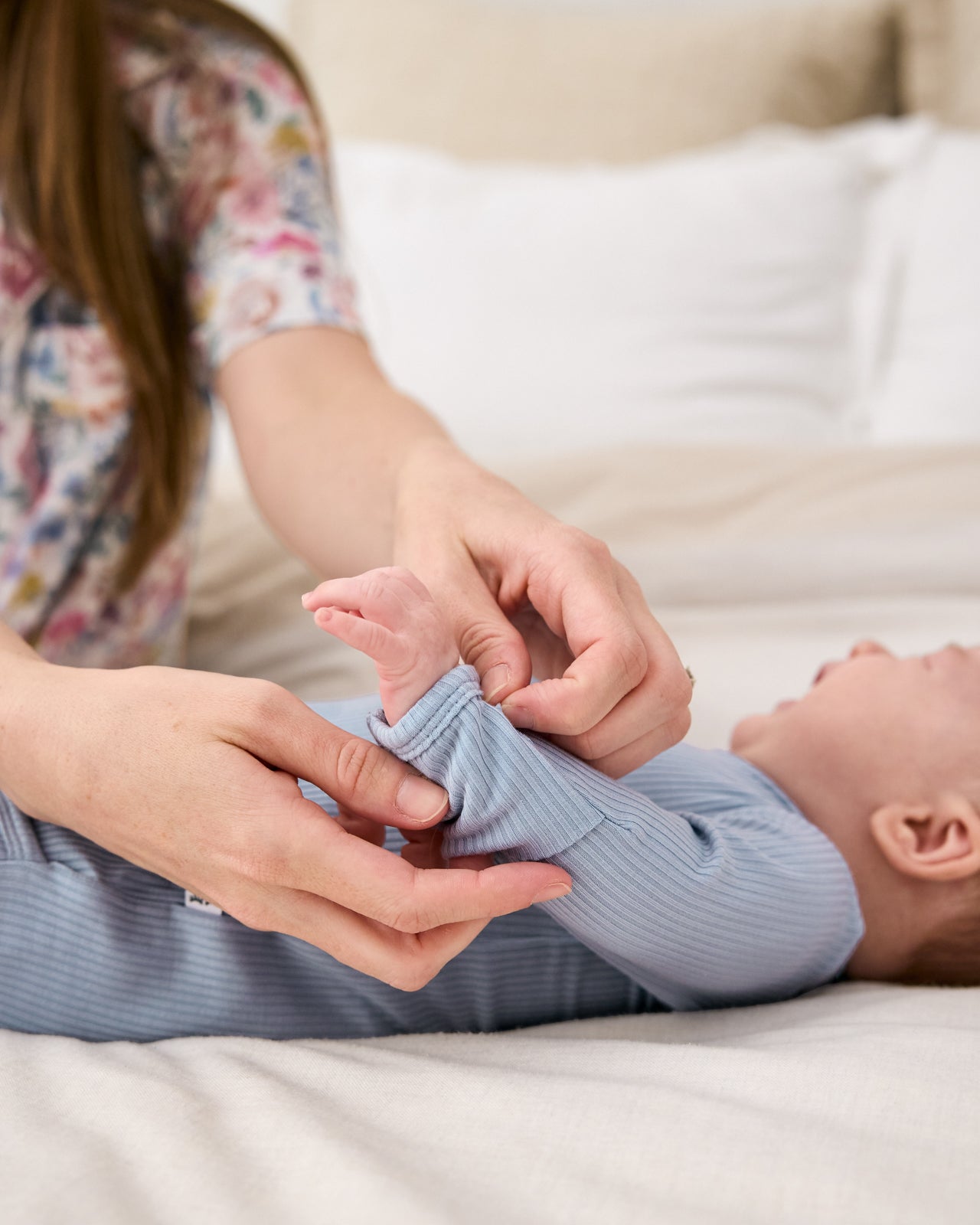Mother adjusting the hand fold over feature on the Light Fog Ribbed Infant Gown
