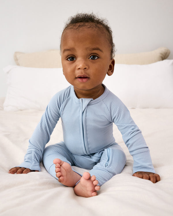 Sitting newborn wearing the Light Fog Ribbed Zippy