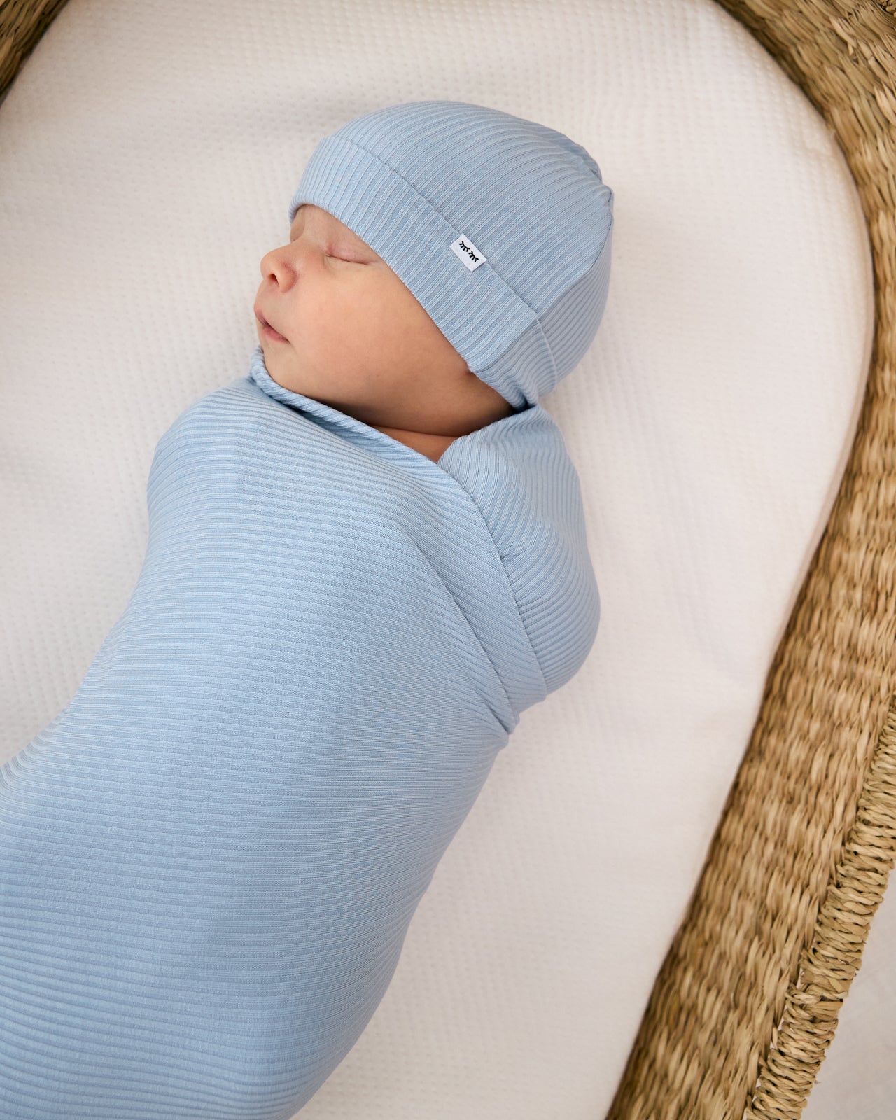 Baby swaddled in the Light Fog Baby Ribbed Swaddle & Infant Beanie Set