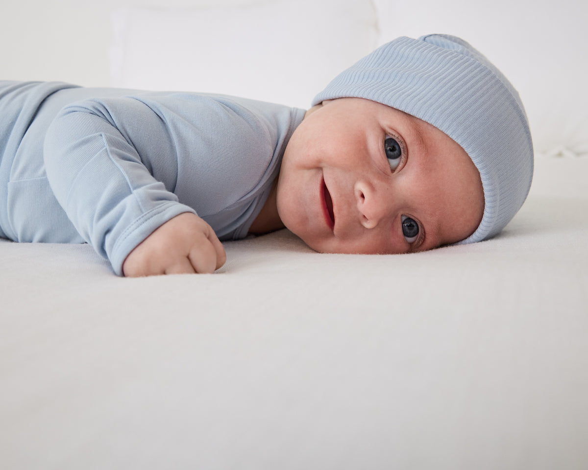 Baby on his tummy wearing the Light Fog Ribbed Infant Beanie