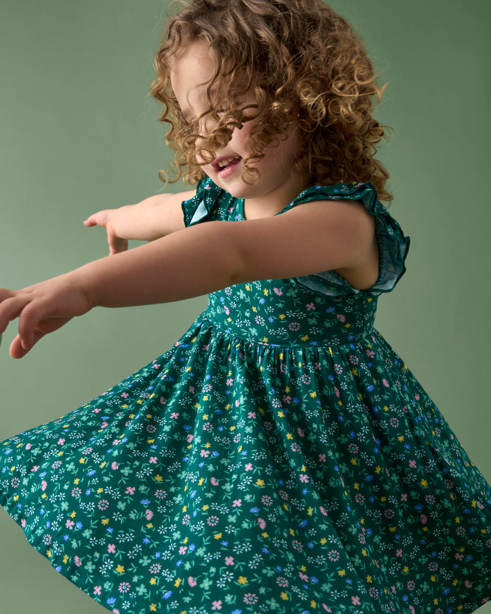 Twirling girl wearing the Emerald Meadow Flutter Twirl Dress