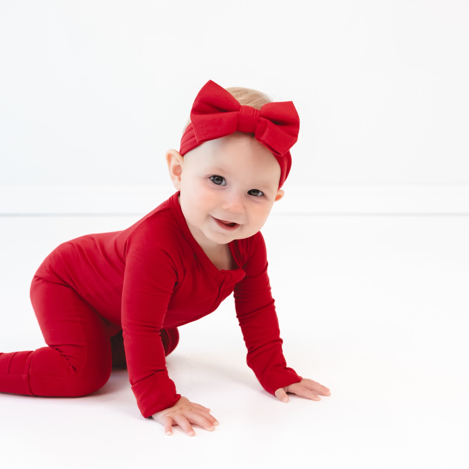 Image of baby crawling while in the Holiday Red Luxe Bow Headband and Holiday Red Zippy