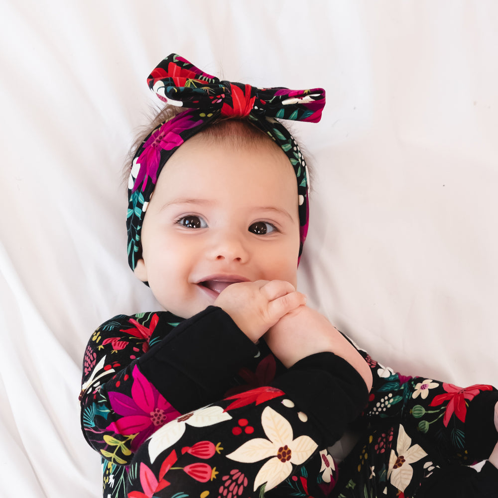 Top view close up image of baby laying down while wearing the Berry Merry Luxe Bow Headband and Zippy