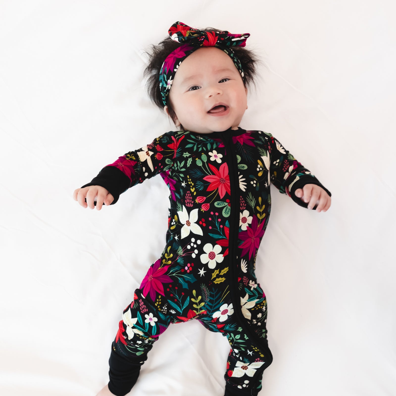 Top view image of a baby laying down while in the Berry Merry Luxe Bow Headband and Zippy