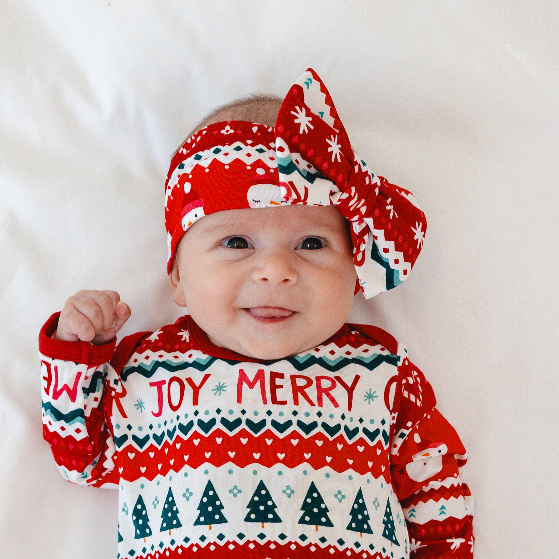 Close up image of an infant wearing a Festive Fair Isle Luxe Bow Headband and Infant Gown