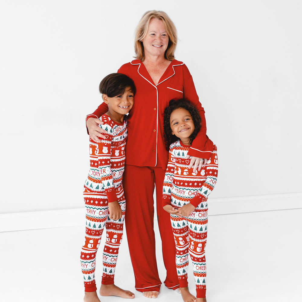 Children on the left and right are in the Festive Fair Isle Two-piece Pajama Set. Female model in the model is in the Holiday Red Women's Long Sleeve Pajama Set