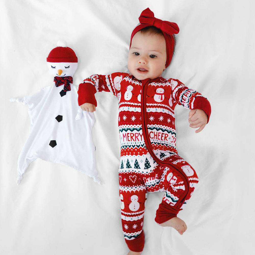 Image of a child laying on a blanket with a Sammy the Snowman Sleepyhead Lovey