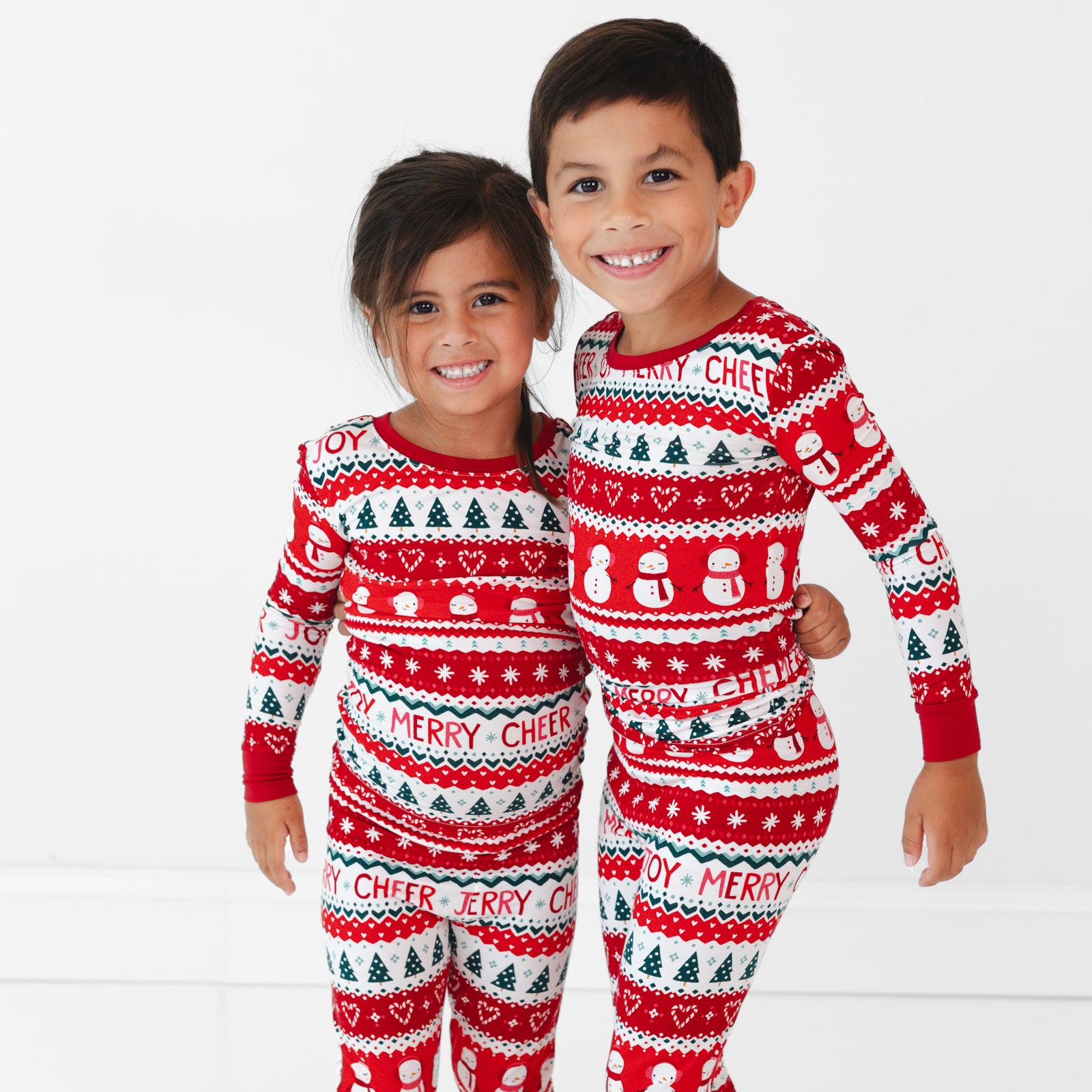 Two children wearing Festive Fair Isle Two-Piece Pajama Sets