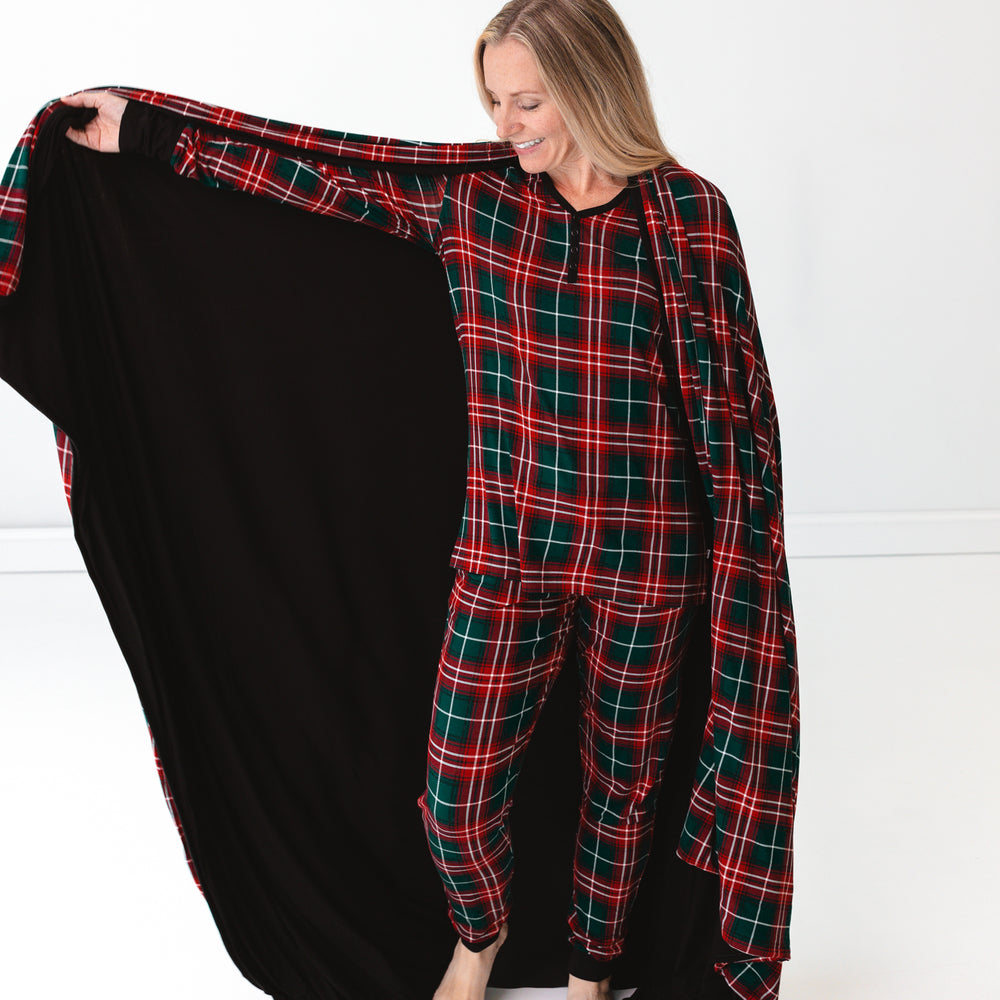 Woman holding out a Fireside Plaid Oversized Cloud Blanket® behind her and wearing Fireside Plaid pajamas