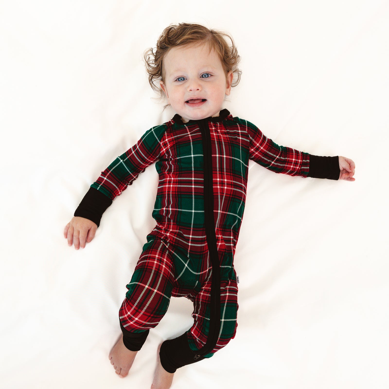 Child laying on a blanket wearing a Fireside Plaid Zippy