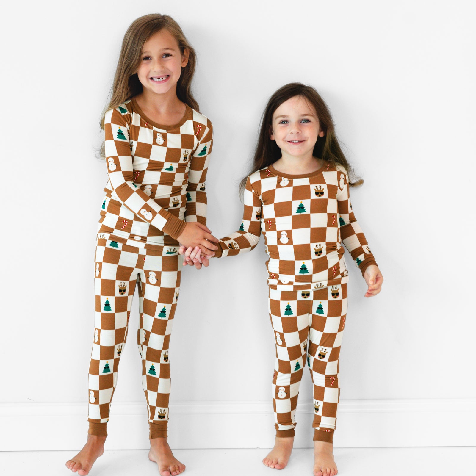 Two smiling girls wearing the Holiday Checks Two-Piece Pajama Set