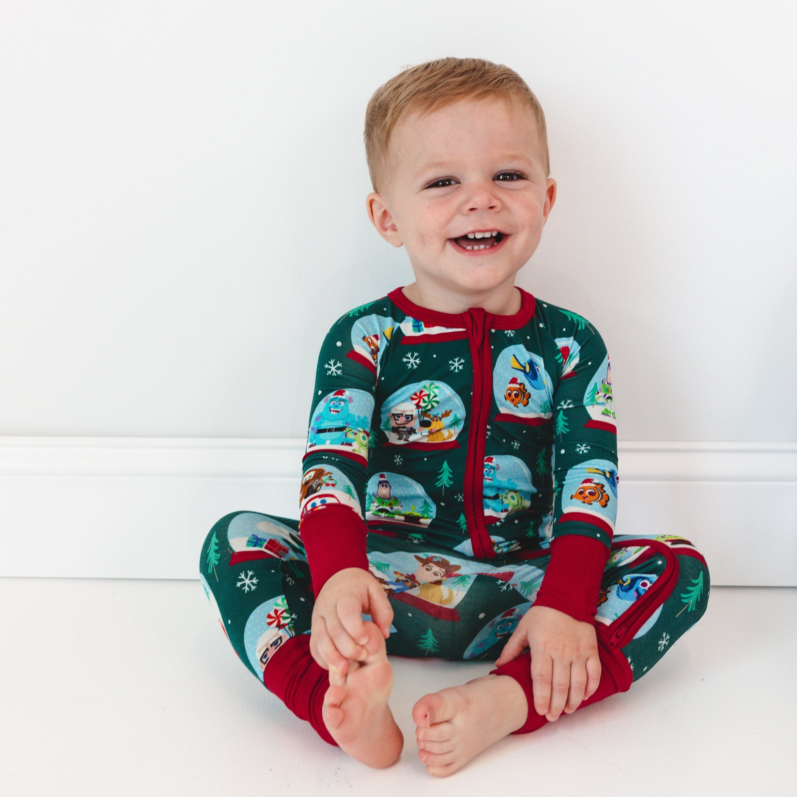 Smiling child sitting while wearing the Disney A Very Pixar Christmas Zippy