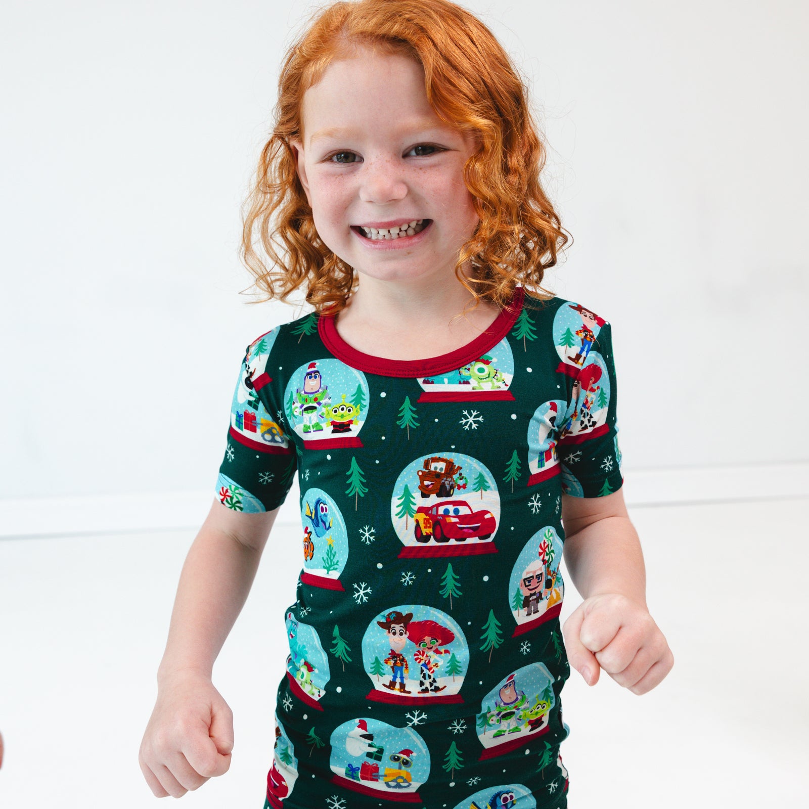 Close up image of child smiling while in the Disney A Very Pixar Christmas Two-Piece Short Sleeve Pajama Set