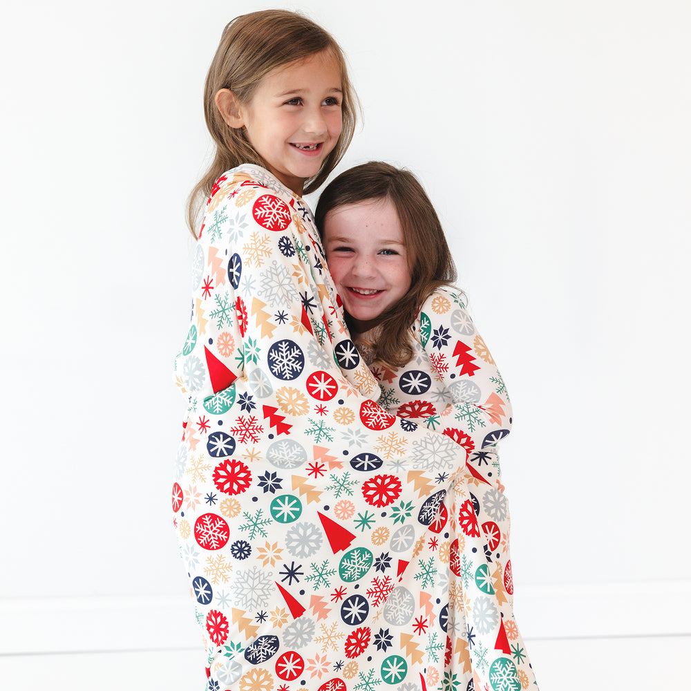 Two children smiling while wrapped together in the Modern & Merry Large Cloud Blanket®