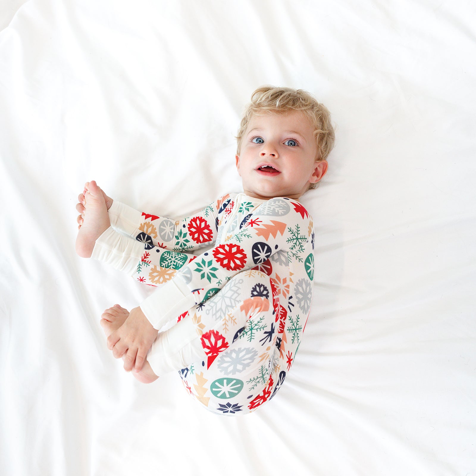 Top view image of child laying down and holding their feet while wearing the Modern & Merry Zippy