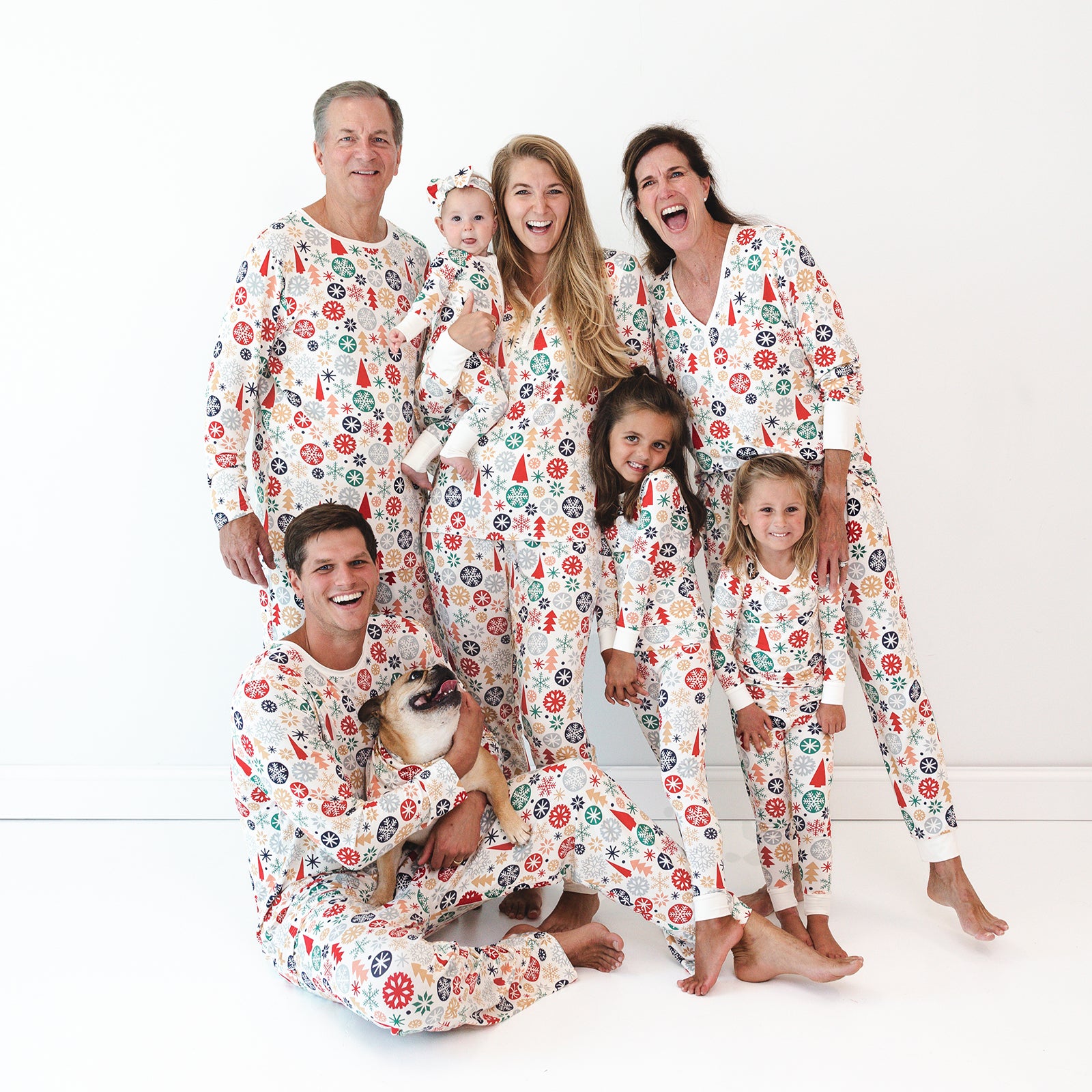 Image of a smiling family of seven wearing the Modern & Merry print. The baby is wearing the Modern & Merry Zippy and the Modern & Merry Luxe Bow Headband