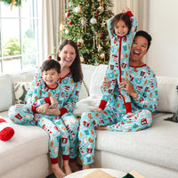 A family of four wearing matching Peppermint Mocha print pajamas on their couch in front of a Christmas tree.