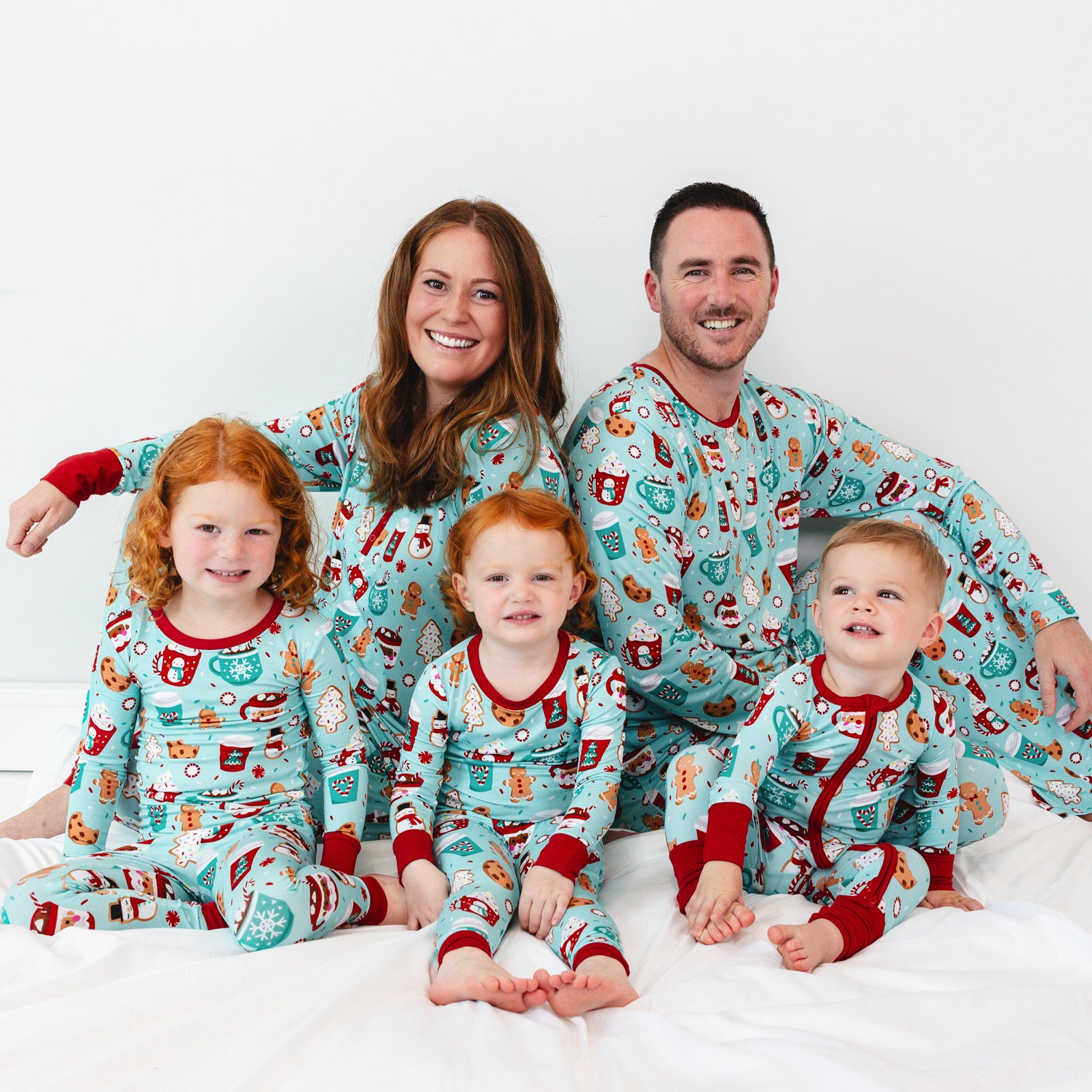 Family of five sitting on a blanket wearing matching Peppermint Mocha pajamas