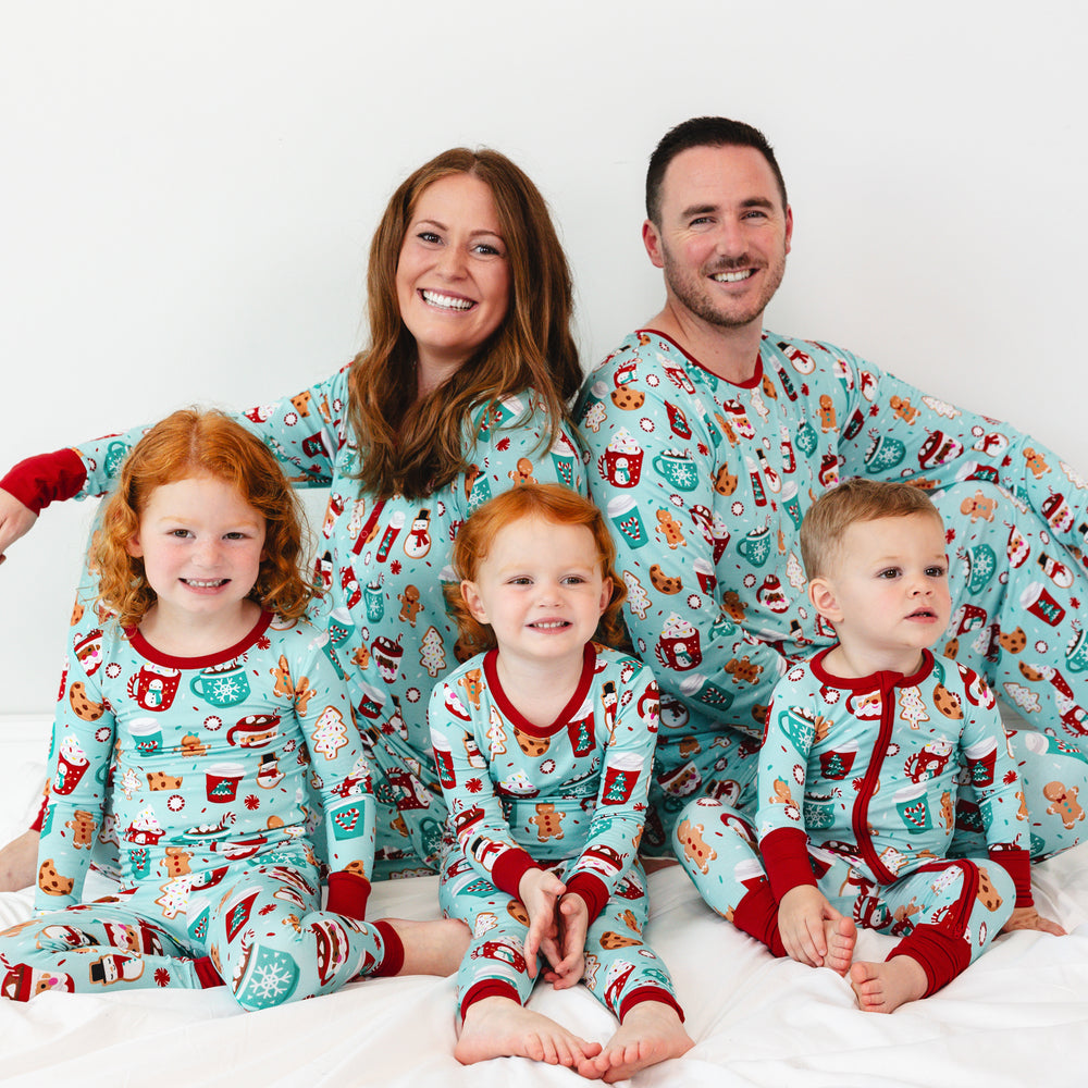 Family of five sitting on a blanket wearing matching Peppermint Mocha pajamas