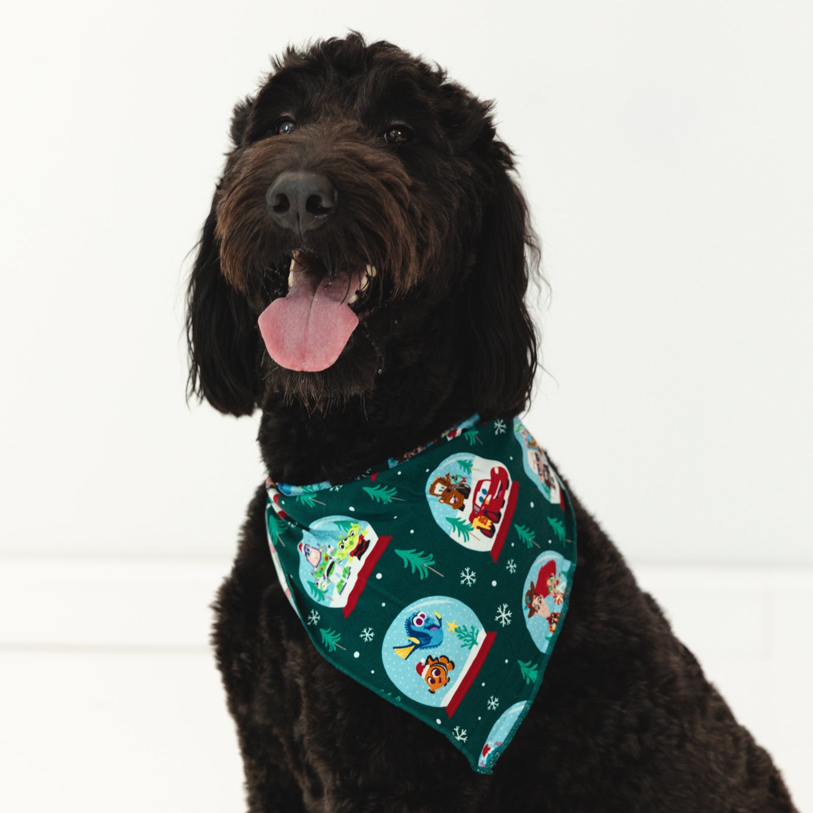 Black dog is wearing the Disney A Very Pixar Christmas Pet Bandana