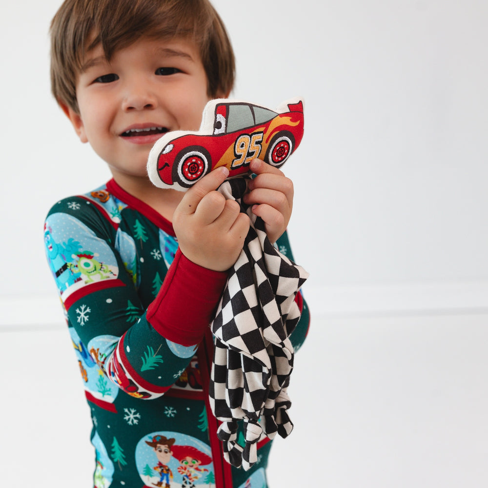 Boy holding the Disney Cars Lightning McQueen Lovey while wearing the Disney A Very Pixar Christmas Zippy