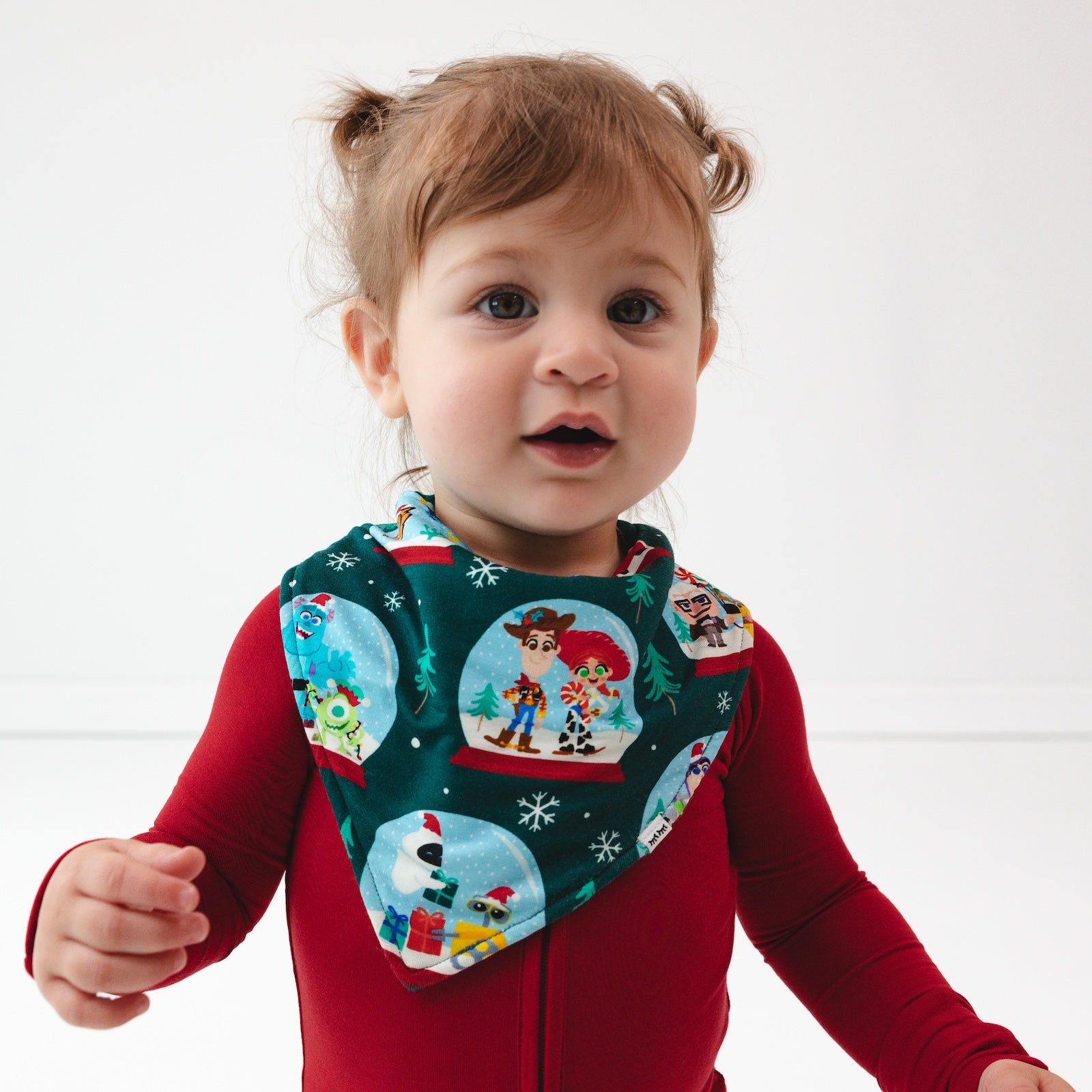 Close up image of a child wearing a Holiday Red Zippy and A Very Pixar Christmas Bandana Bib