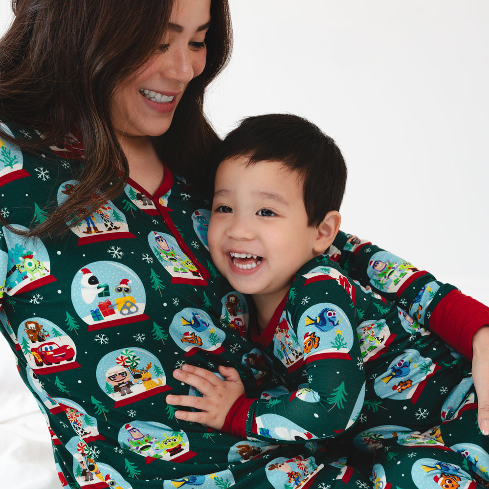 Smiling mother and song wearing the Disney A Very Pixar Christmas print. Female model is wearing the Disney A Very Pixar Christmas Women's Pajama Top and boy is wearing the Disney A Very Pixar Christmas Two-piece Pajama Set