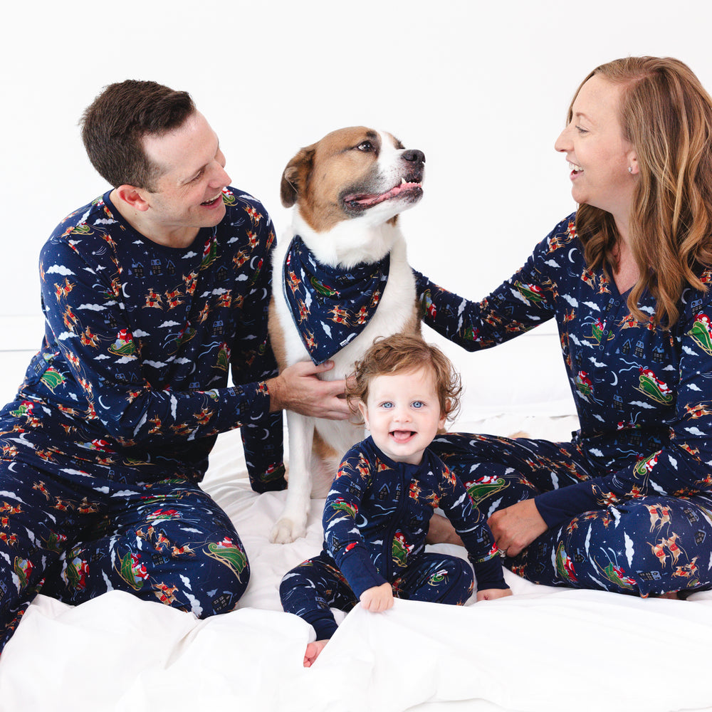 Family of three and a dog wearing matching Santa's Sleigh pajamas