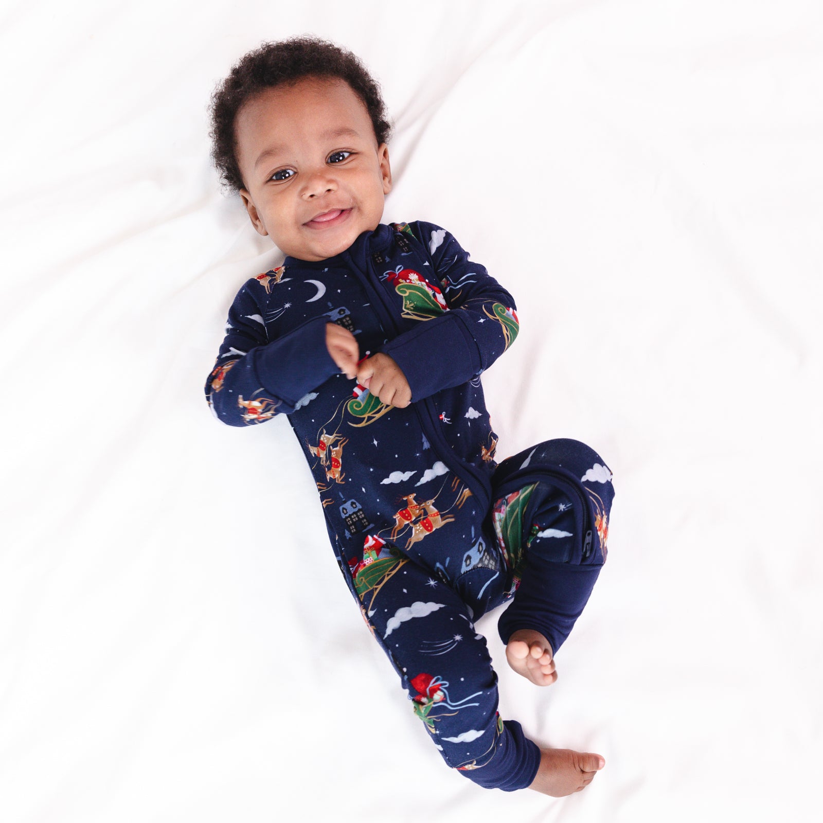 Image of a child laying on a blanket wearing a Santa's Sleigh Zippy