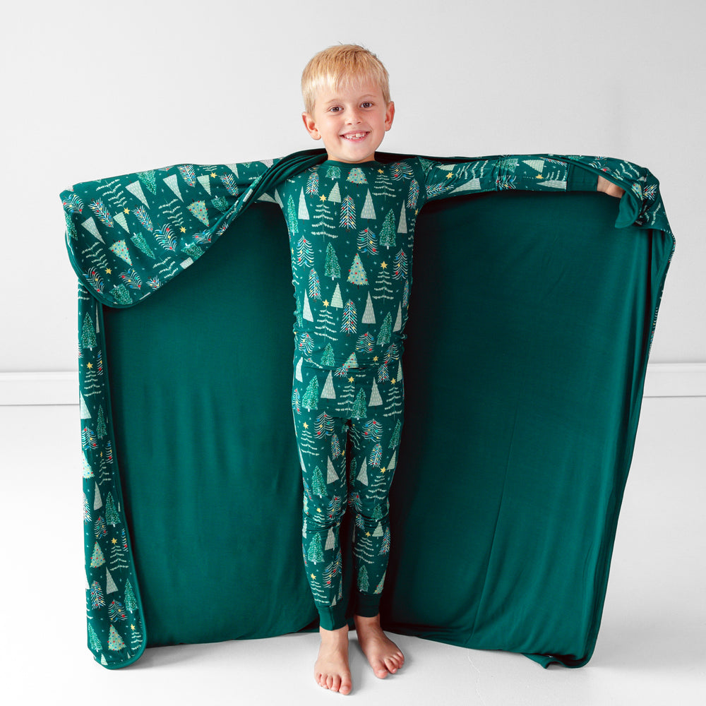 Smiling child posing with the Green Twinkling Trees Large Cloud Blanket® while displaying the inside green color