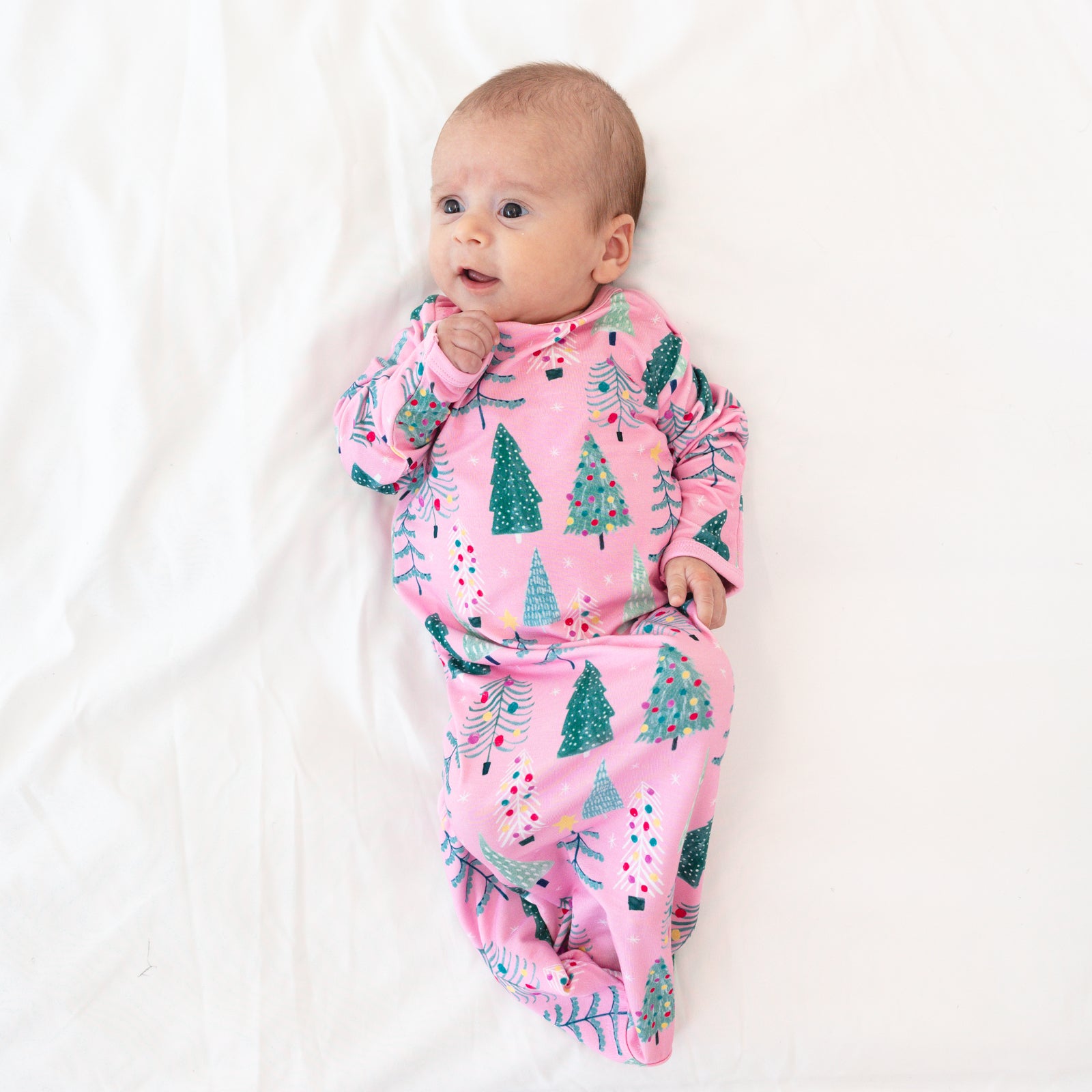 Image of an infant laying on a blanket wearing a Pink Twinkling Trees Infant Gown