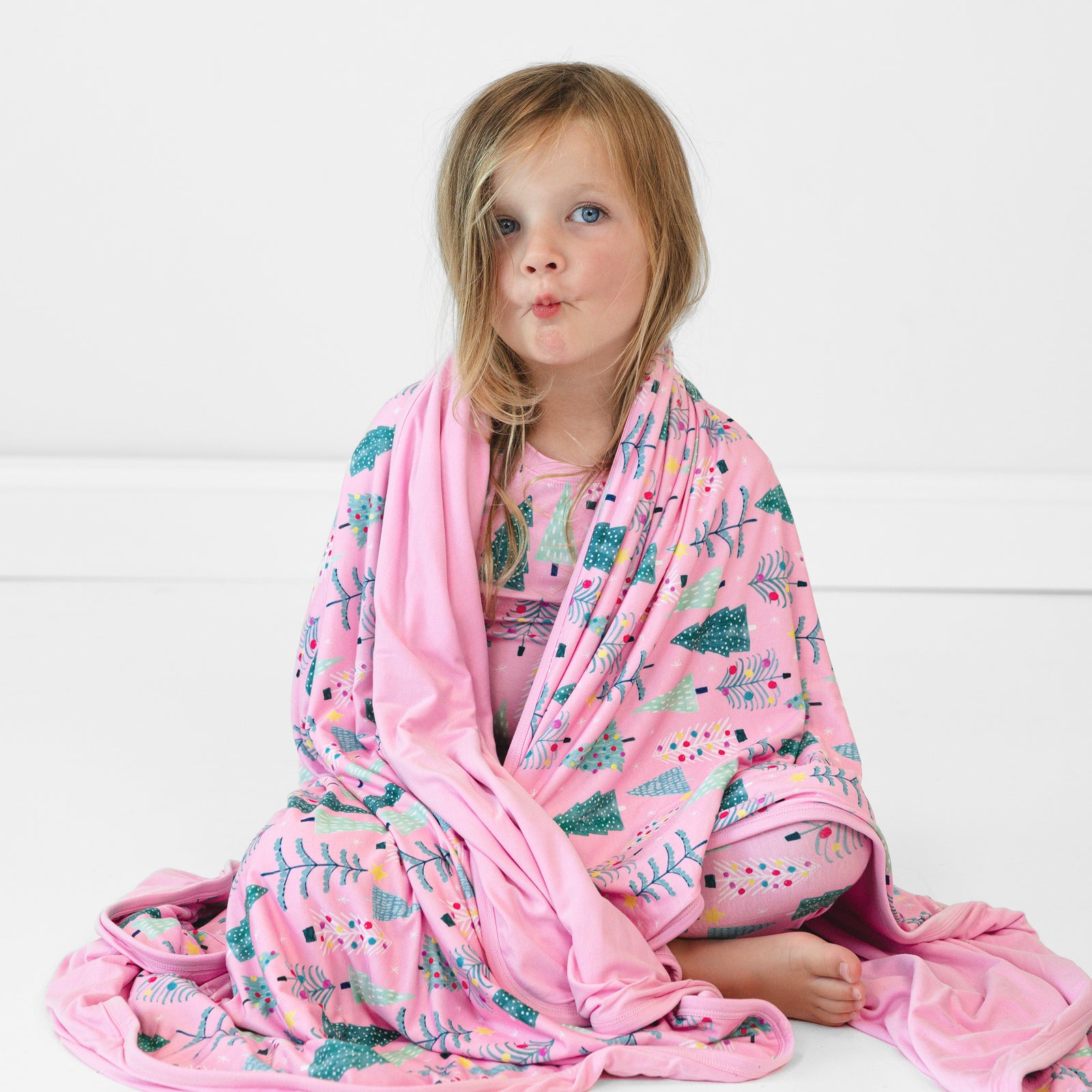 Alternate image of a child sitting on the ground with a Pink Twinkling Trees Large Cloud Blanket draped over them and wearing matching pajamas