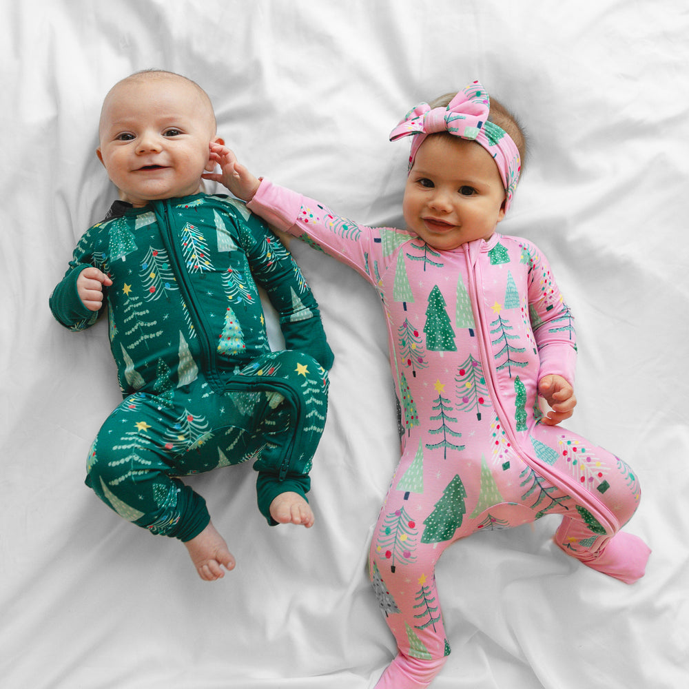 Two children laying on a blanket wearing matching Pink and Green Twinkling Trees Zippies