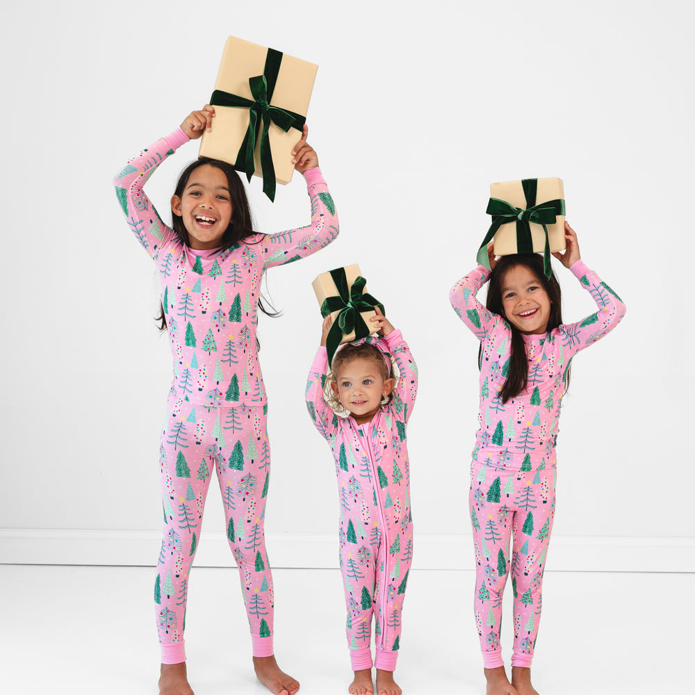 Image of three children holding presents and wearing matching Pink Twinkling Trees pajamas